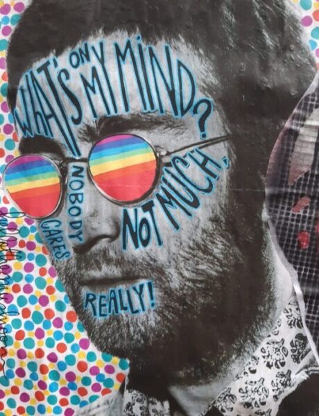 A surreal image of a man wearing rainbow coloured glasses with writing on his face.