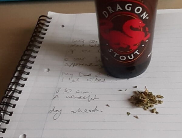 A bottle of dragon Stout & weed on a writing pad