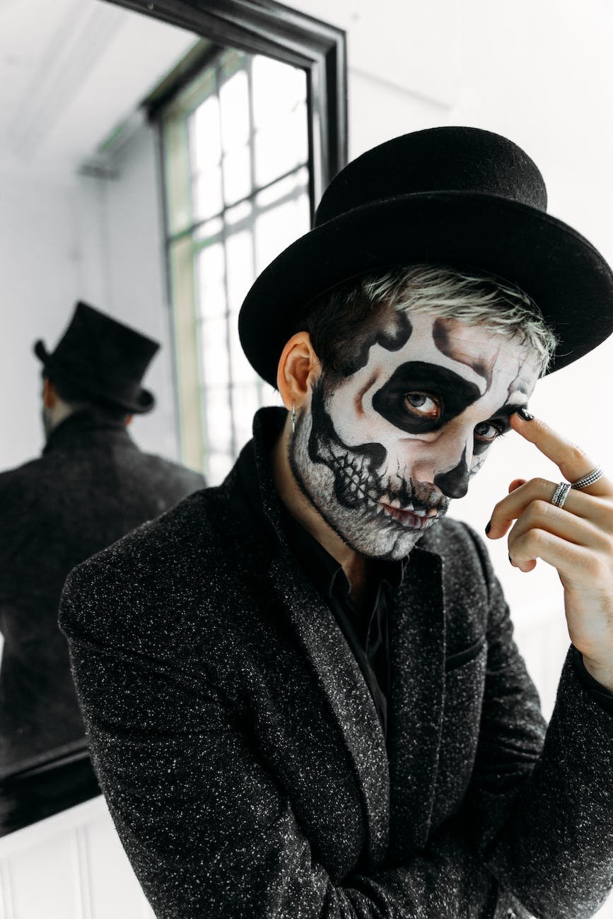 man with black hat and black coat with a scary face paint