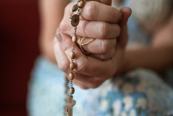 a woman holding a rosary while praying