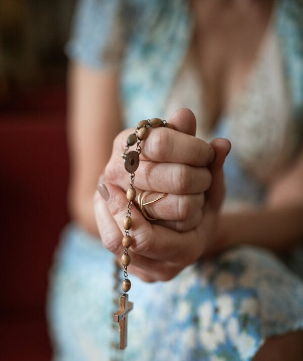 a woman holding a rosary while praying