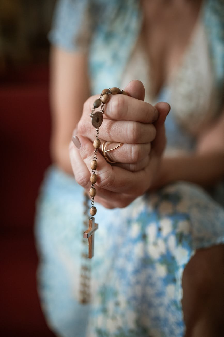 a woman holding a rosary while praying