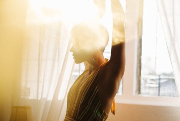 slender woman dancing near window in bright sunshine