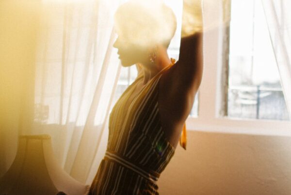 slender woman dancing near window in bright sunshine