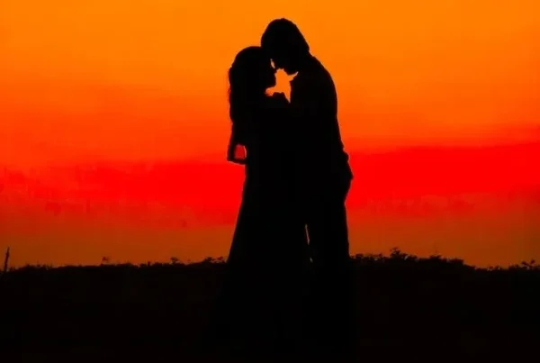 A man and a woman holding tight amidst a sunlit background