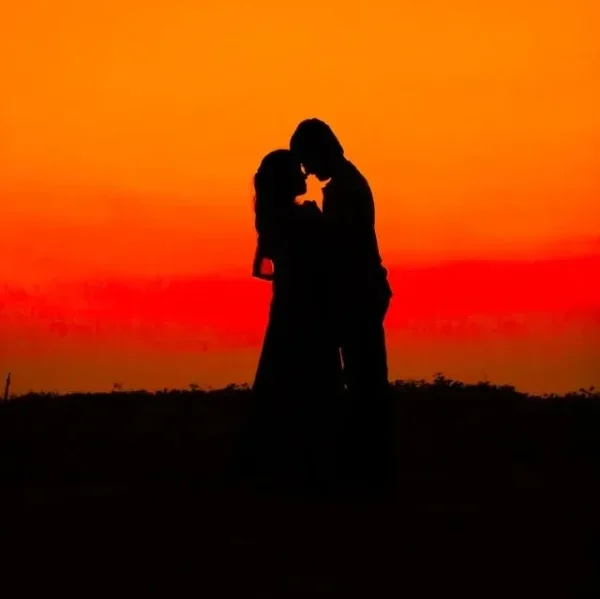 A man and a woman holding tight amidst a sunlit background