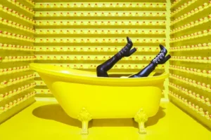 a yellow room and yellow bath with two legs wearing black boots potruding out