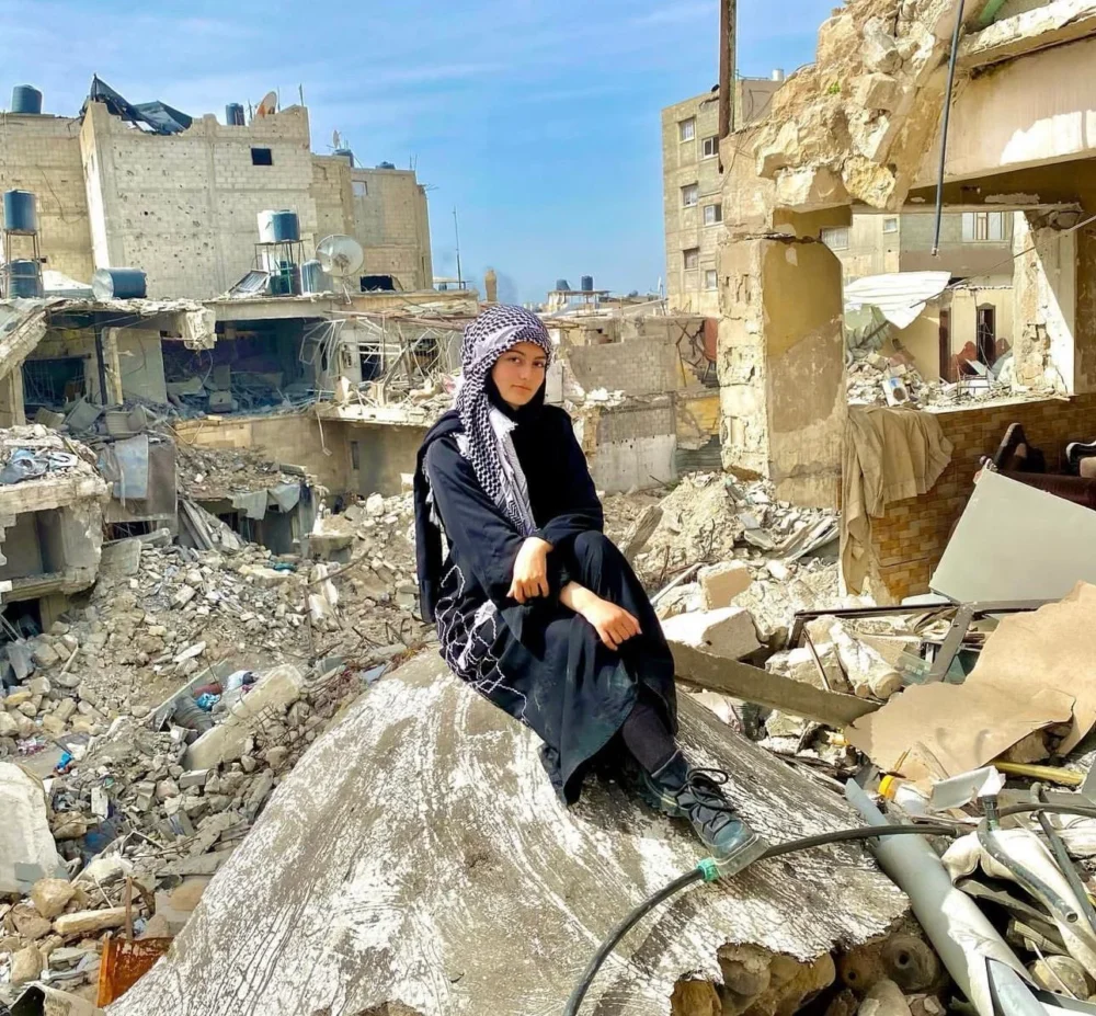 A young woman in Gaza sitting amidst rubble