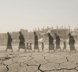A desolate landscape with silhouettes of people walking through the ruins.