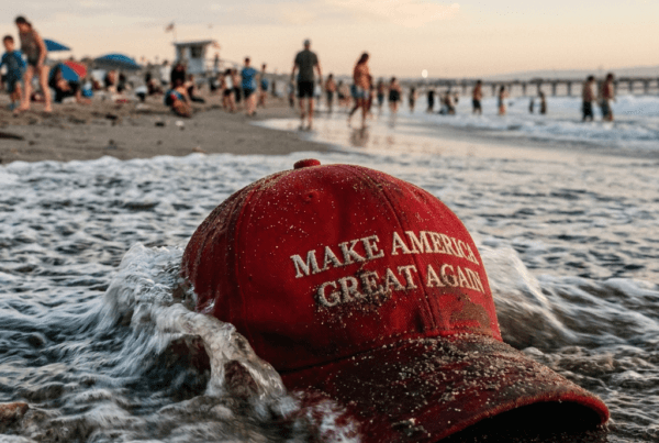 Wet "MAGA" cap washed ashore on a busy beach.